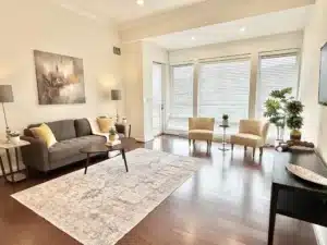 Living room in residence 648 with a sofa and armchairs beside tall windows
